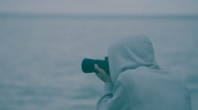 Photographer in Hoodie Capturing Ocean Landscape