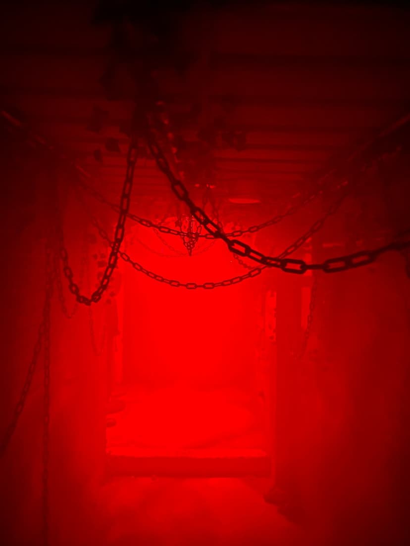 Thick iron chains suspended in a dark room illuminated by a saturated red light with heavy shadows.