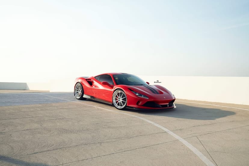 Red Ferrari F8 Tributo parked on a concrete rooftop under a bright clear sky with long soft shadows.