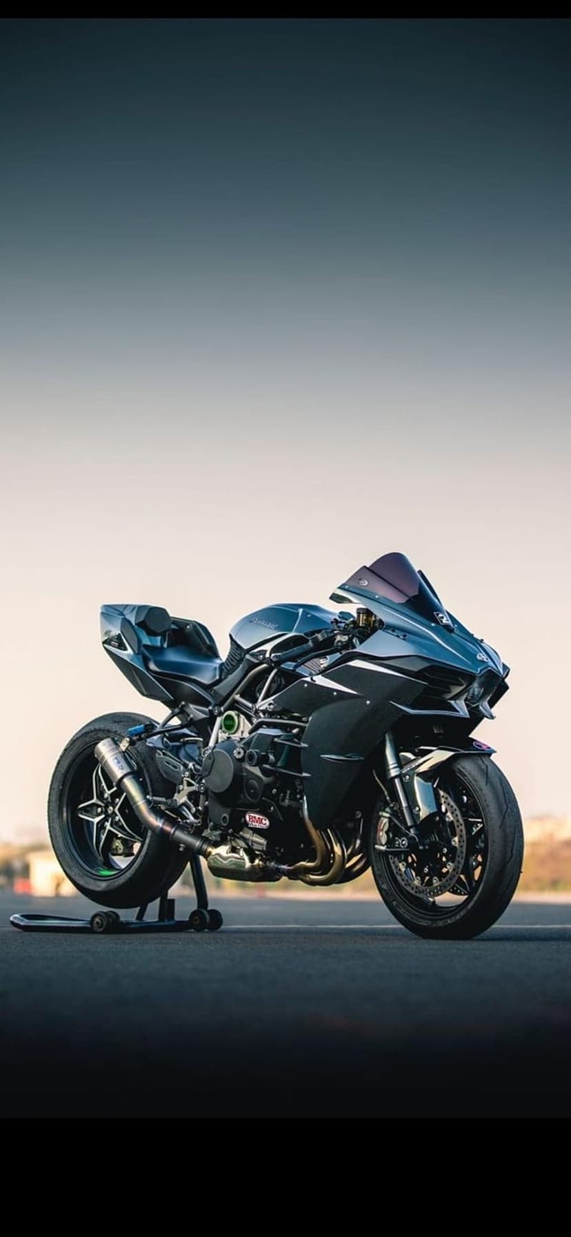 Kawasaki Ninja H2R hyperbike on a rear stand featuring aerodynamic wings and a black finish against twilight.