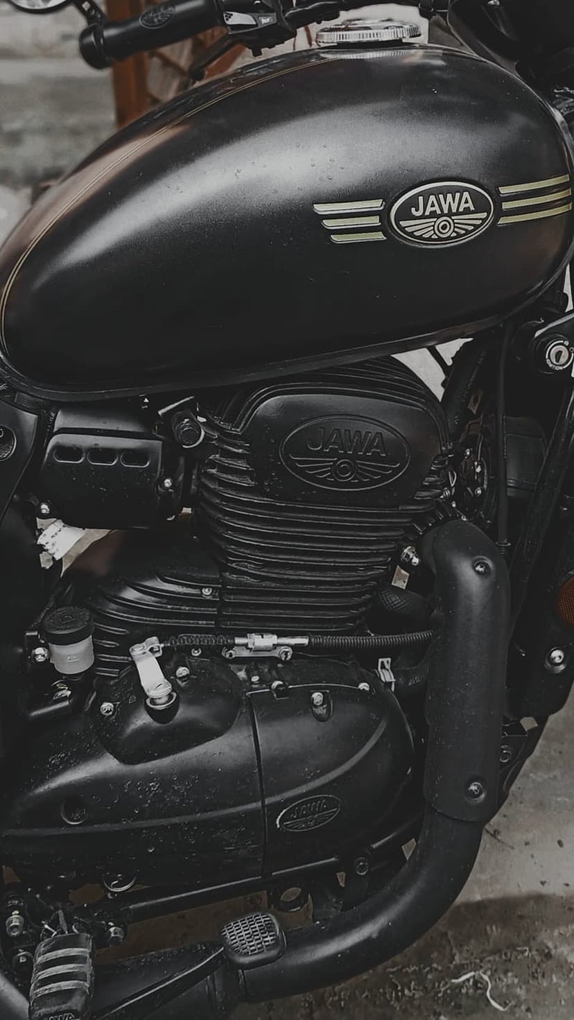 Jawa motorcycle engine with ribbed cooling fins and a matte black fuel tank featuring an embossed brand logo.