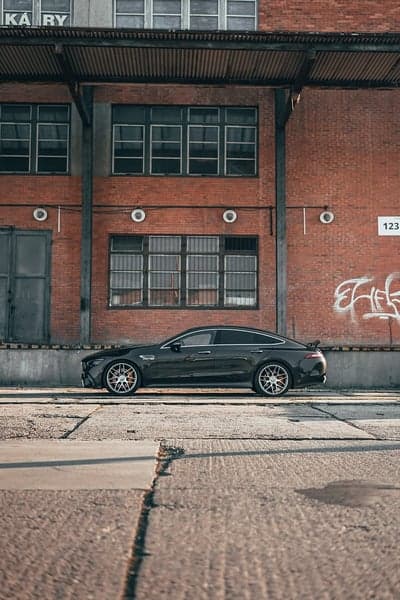 Dark AMG GT 4-Door Coupe Parked by Industrial Brick Building
