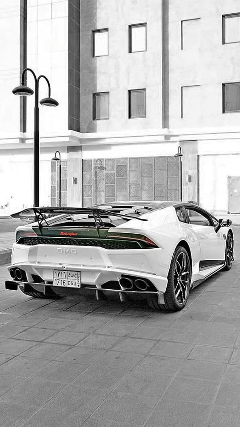 White Lamborghini Huracán Performante with a large rear wing parked on a stone street by a modern building.
