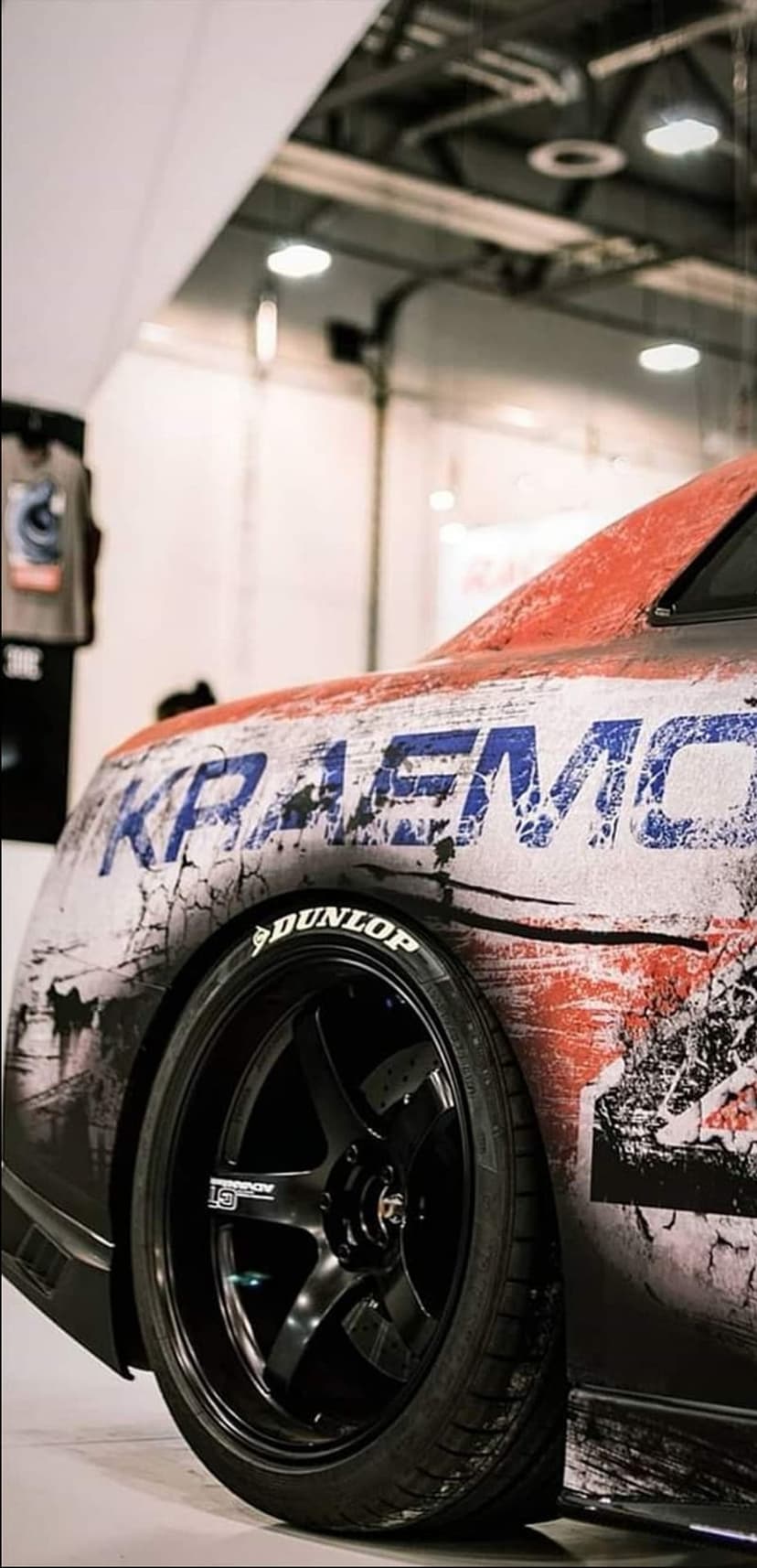 Rear fender of a customized car with blue KRAEMO decal and a black alloy wheel fitted with a Dunlop tire.