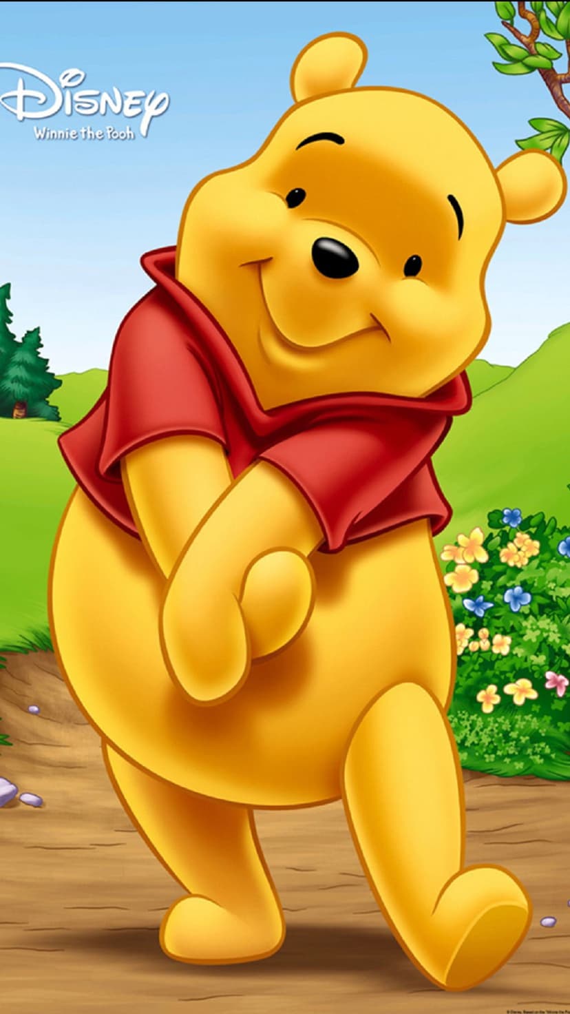 Winnie the Pooh smiles in a green forest with red, blue, and yellow flowers under a sunny woodland canopy.
