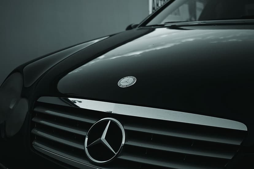 Mercedes-Benz three-pointed star emblem and textured grille shown in a monochrome close-up automotive shot.
