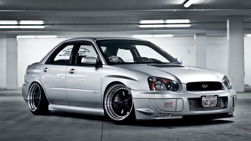 Silver stanced Subaru Impreza WRX STi with deep dish wheels in a minimalist concrete parking garage.