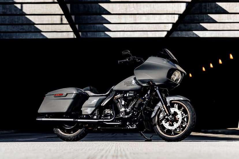 Gray Harley-Davidson Road Glide motorcycle parked in a dark industrial space with bronze wheels and bokeh lights.