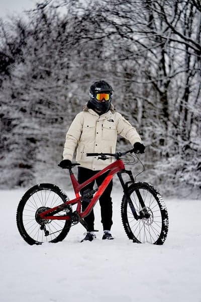 Mountain biker in snow with red bike and protective gear
