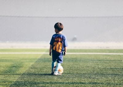 Young boy in Messi jersey with soccer ball on field