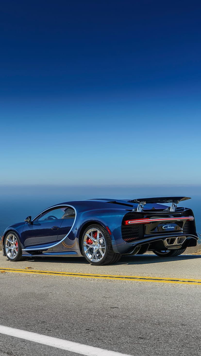 Bugatti Chiron hypercar parked on a scenic coastal road overlooking a calm blue ocean under a clear sky.