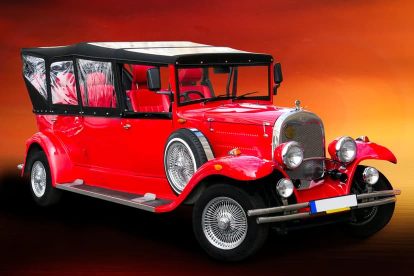 Red vintage convertible car with spoked wheels and chrome trim against a warm orange and yellow gradient background.