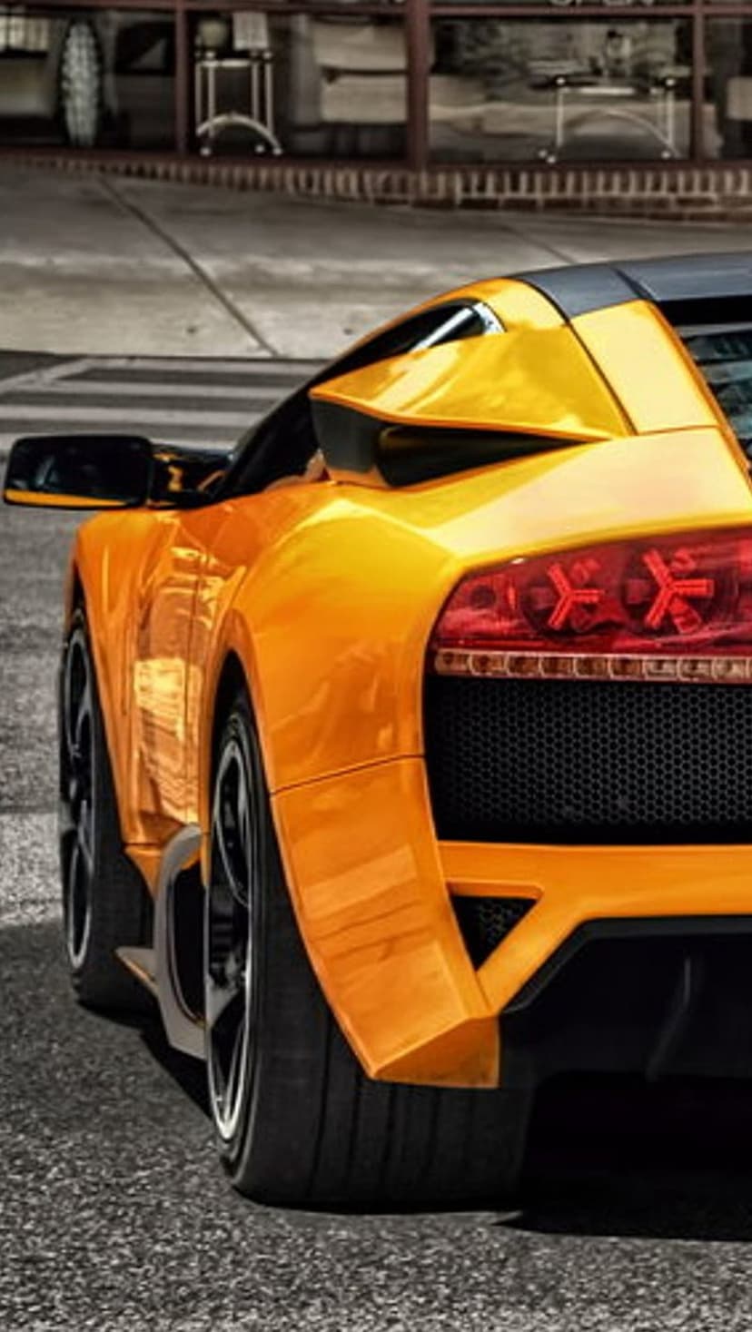 Rear view of an orange Lamborghini sports car featuring sharp LED taillights and wide performance tires.