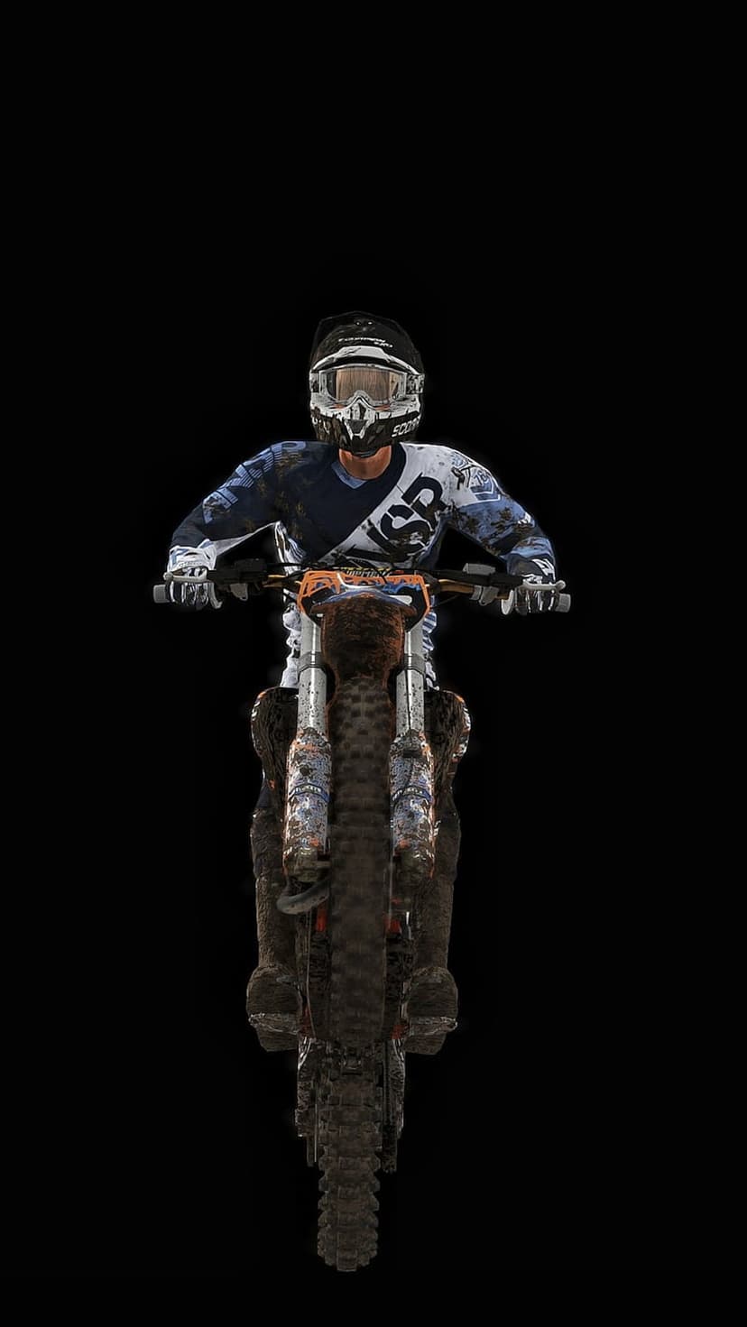 Motocross rider on a mud-splattered dirt bike faces forward against a solid black background with visible grit.