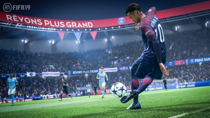 Neymar Jr in a blue jersey kicks a soccer ball on a green field in a bright, crowded stadium.