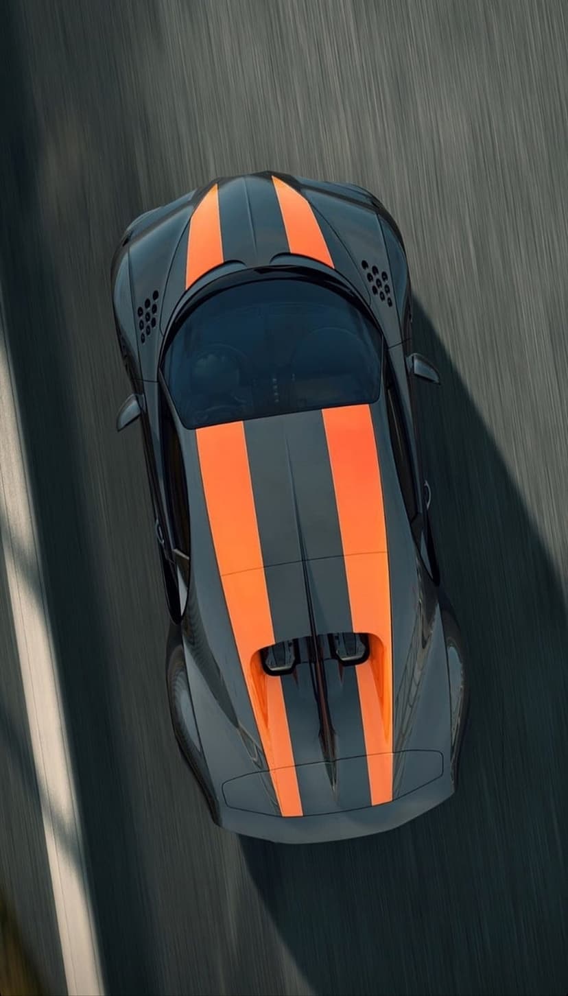 Black sports car with orange racing stripes driving on asphalt, captured from a top-down aerial perspective.