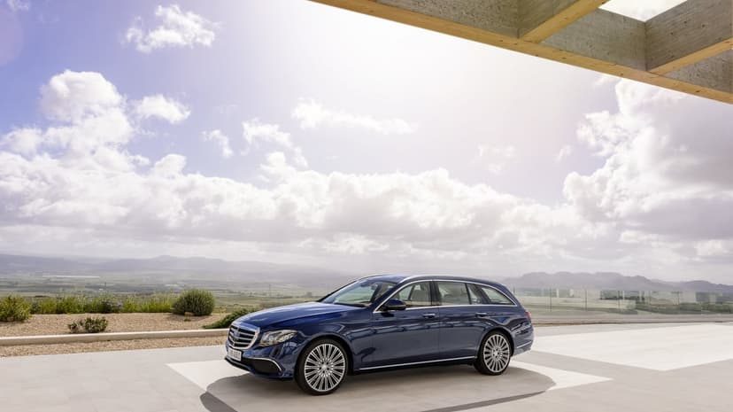 Navy blue Mercedes-Benz E-Class Estate on a stone terrace with a scenic valley and mountain background.