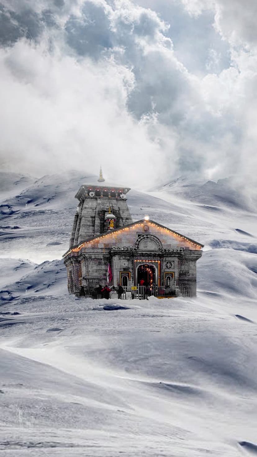 Kedarnath Temple stands in a snow-covered valley surrounded by jagged Himalayan peaks under a dark cloudy sky.