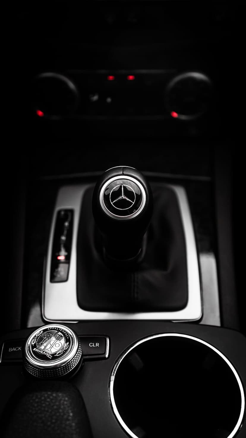 Mercedes-Benz gear shifter with star logo and AMG control knob on a dark center console in black and white.