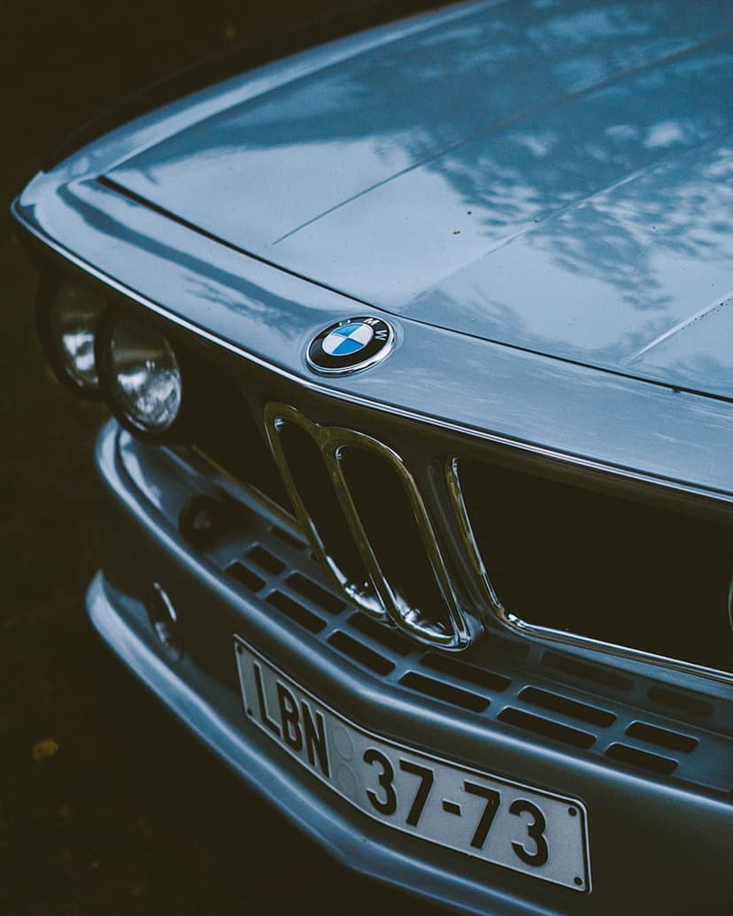 Light blue vintage BMW front end featuring the iconic kidney grille, round headlights, and a silver hood emblem.