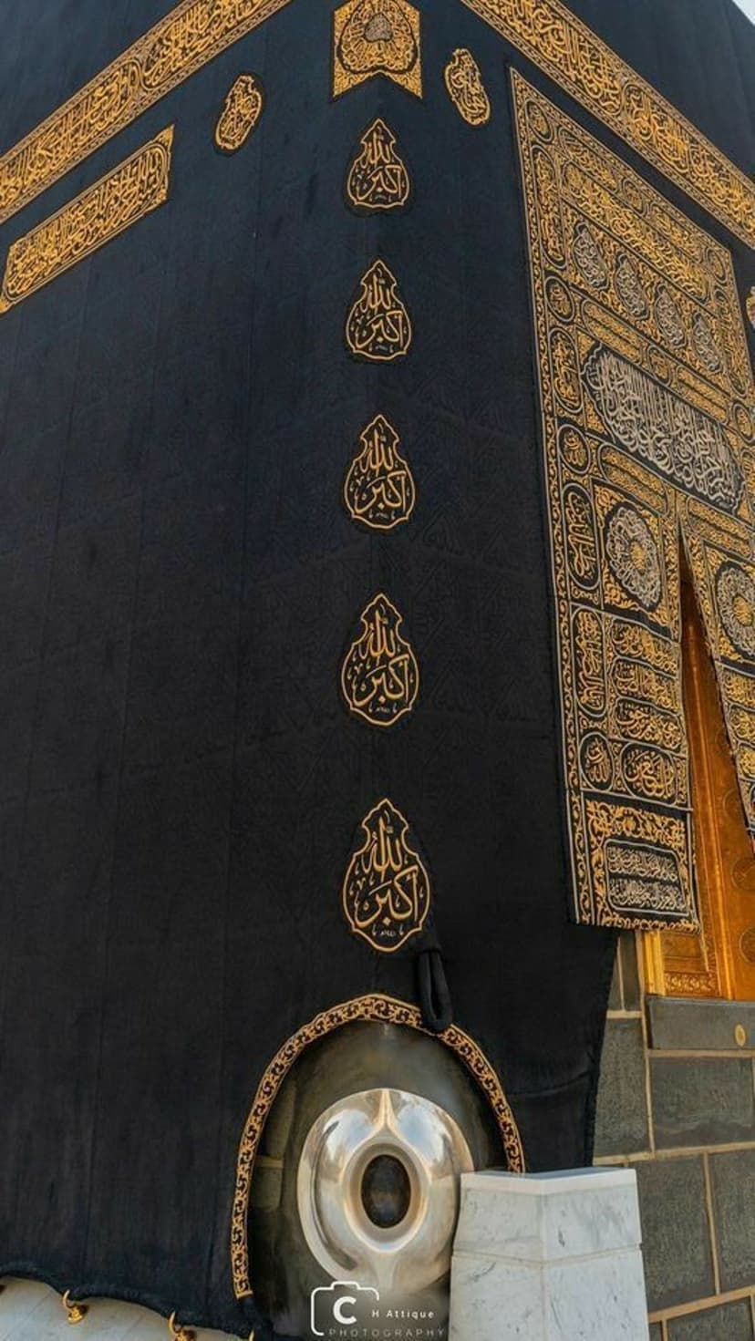 Hajar al-Aswad set in the corner of the Kaaba with golden Arabic calligraphy on black Kiswah fabric.