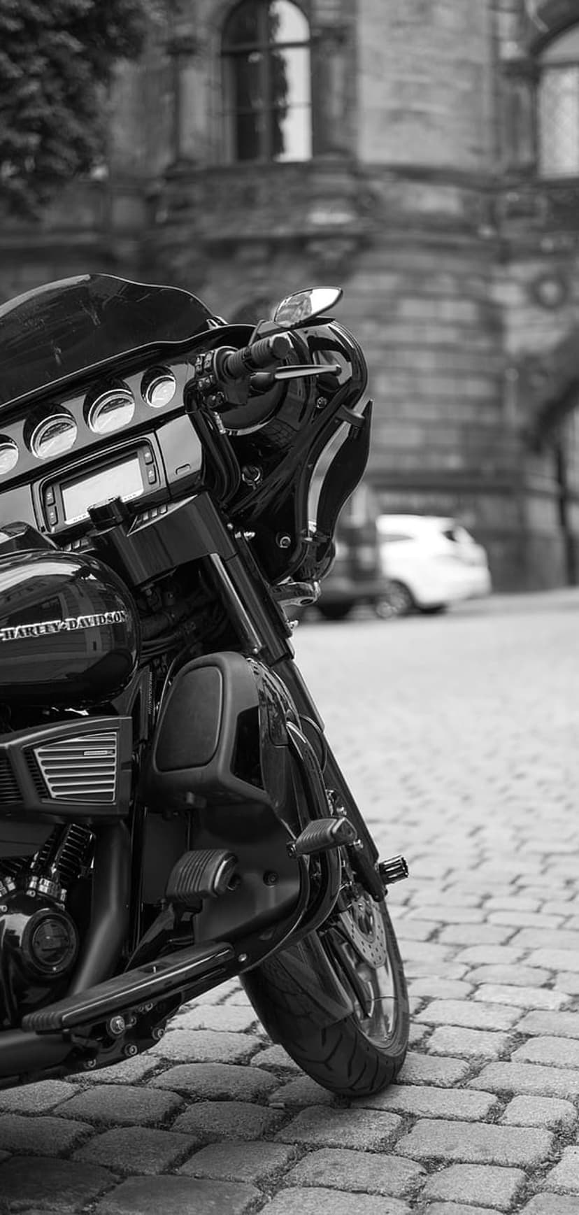 Harley Davidson motorcycle with detailed engine and front fairing parked on a textured cobblestone city street.