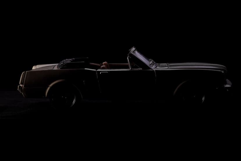 Vintage convertible car silhouette with rim lighting against a black background for mobile phone screens.