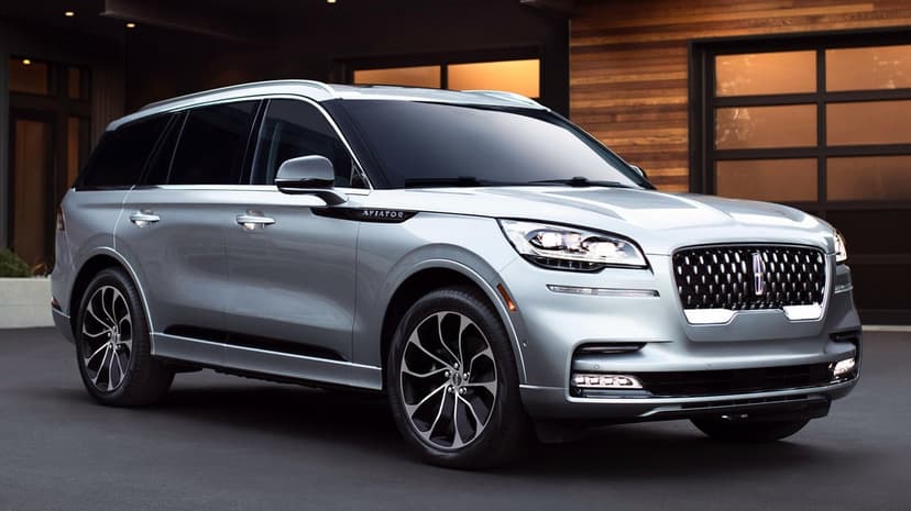 Silver Lincoln Aviator luxury SUV parked in front of a modern wood-paneled home with warm evening lighting.