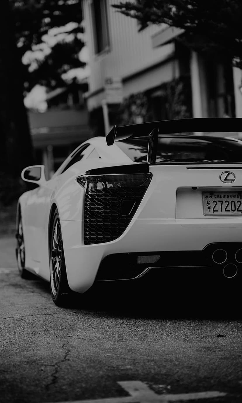 Lexus LFA rear view with iconic taillights, large spoiler, and exhaust pipes in high-contrast monochrome.