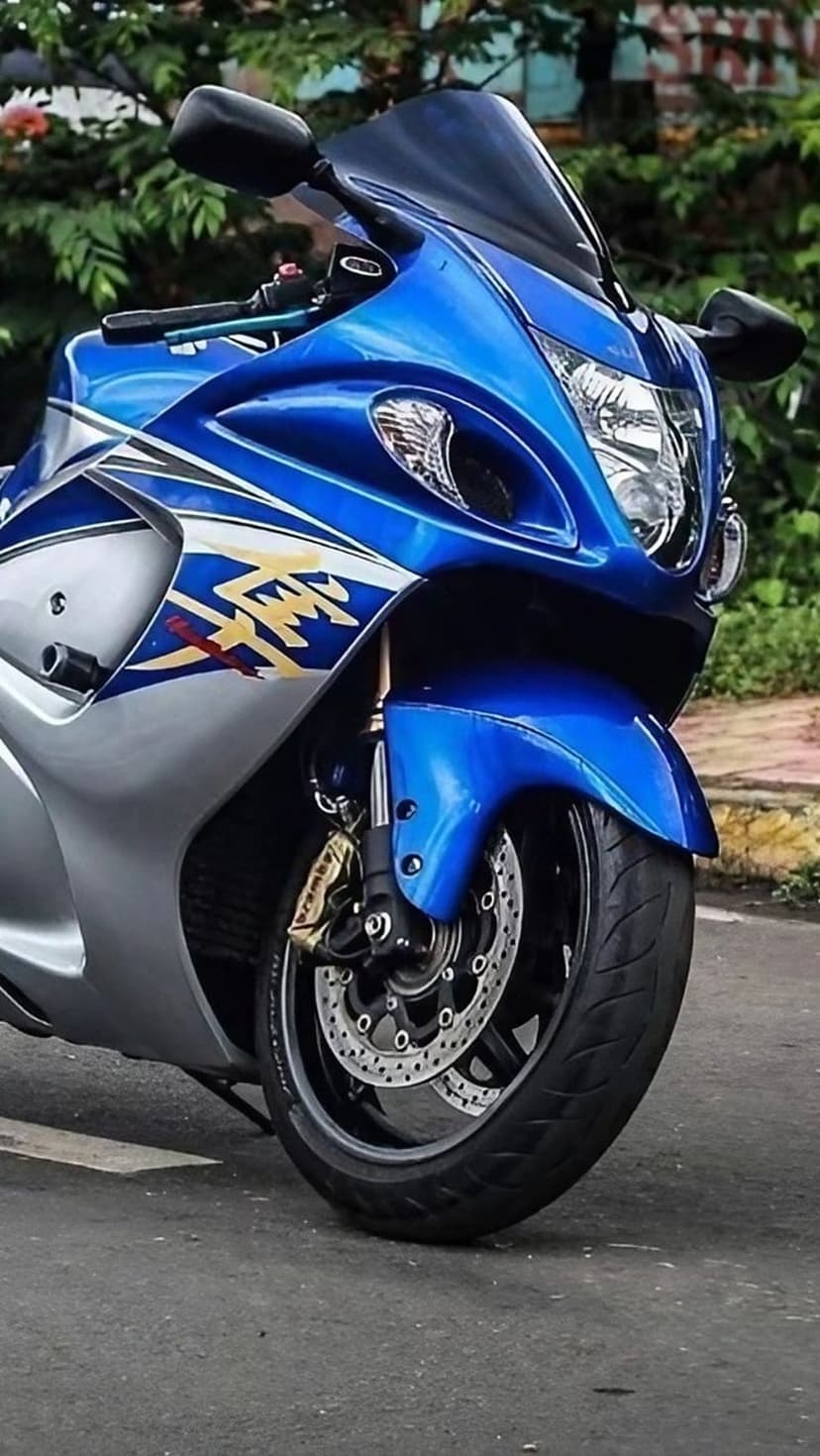 Suzuki Hayabusa motorcycle front view featuring blue fairings, gold GSX logos, and dual headlights in soft light.
