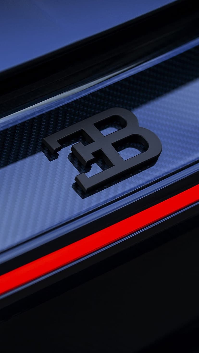 Black Bugatti EB logo mounted on a dark blue carbon fiber surface with a vibrant red stripe accenting the base.