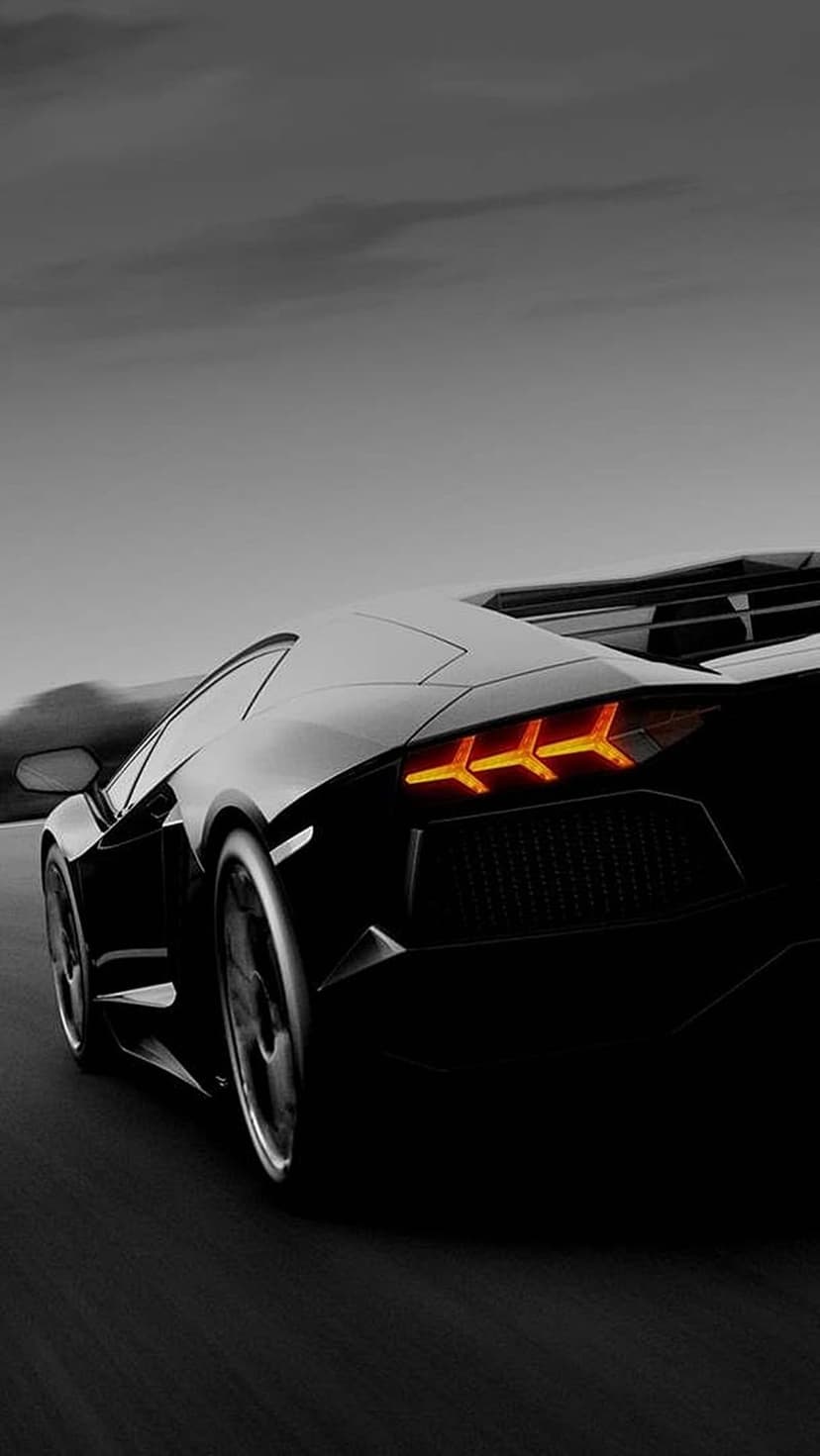 Lamborghini Aventador rear taillights glowing orange on a dark road with motion blur under a moody evening sky.
