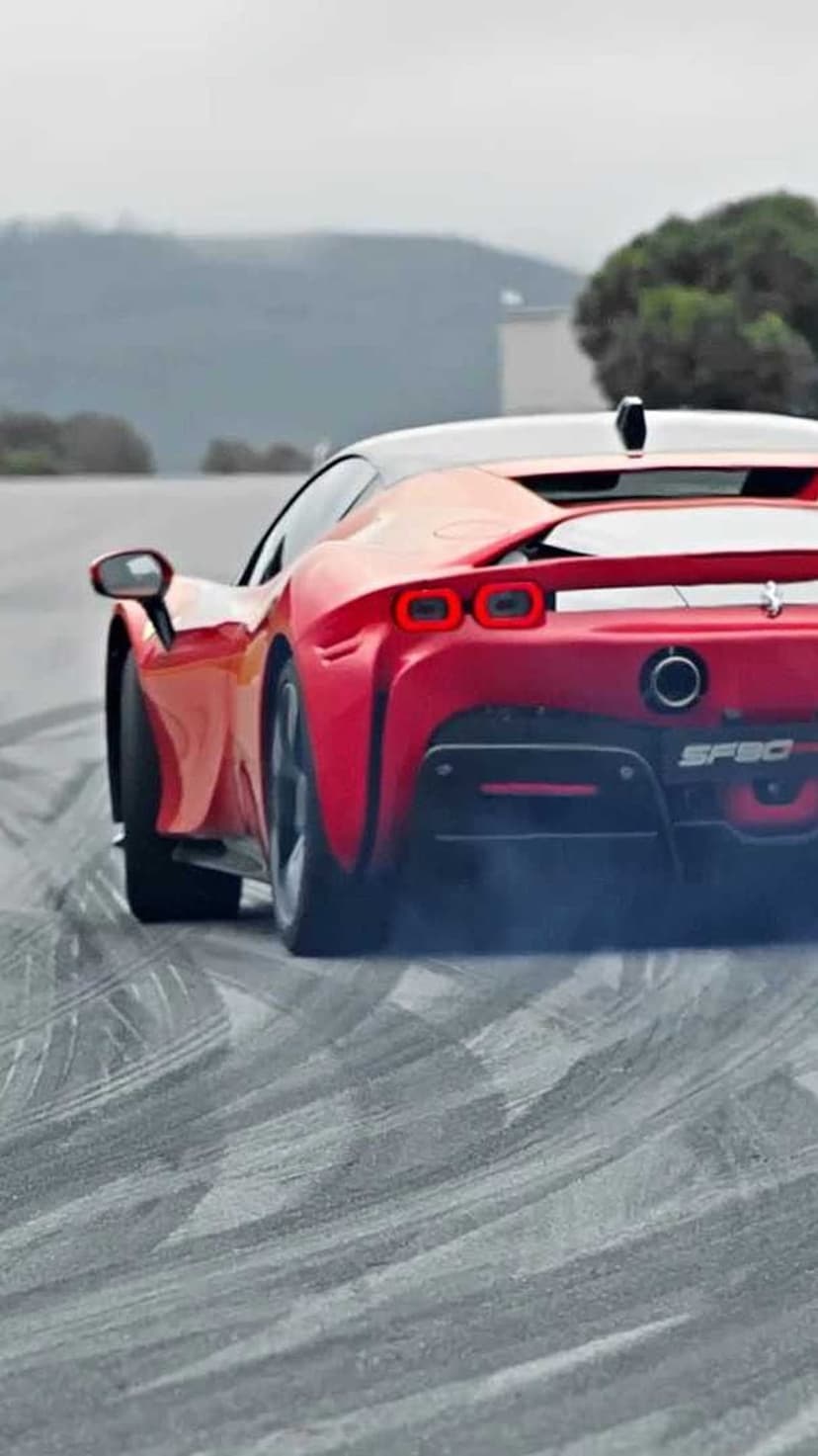 Ferrari SF90 supercar performing a rear tire burnout with thick white smoke on a textured grey asphalt surface.