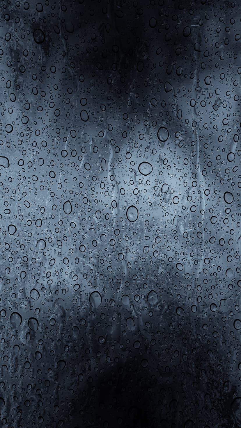 Clear water droplets of various sizes rest on a dark, cool-toned glass surface with a soft-focus background.