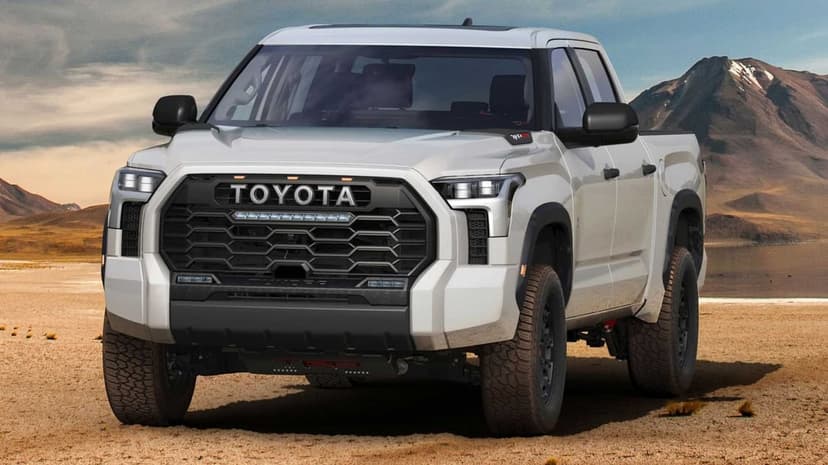 White Toyota Tundra TRD Pro off-road truck parked on sandy desert ground with distant mountains and a blue sky.