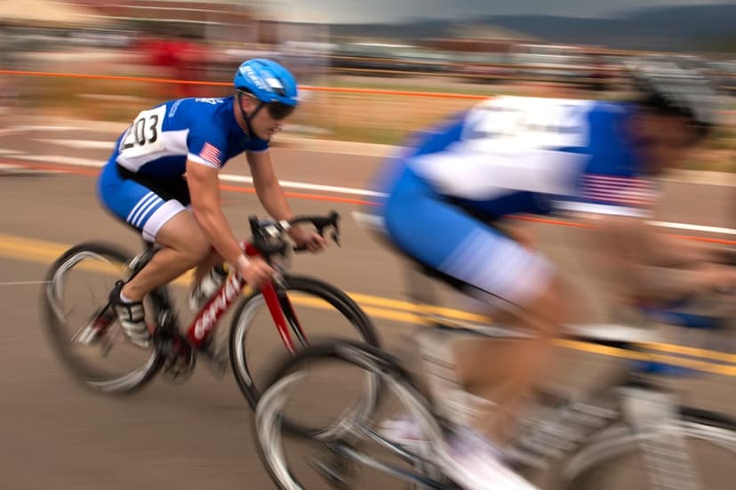 Pro cyclist in a blue jersey races a red bike through motion blur during a competitive road cycling event.