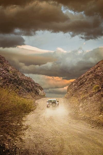 Off-road adventure through a rocky canyon under dramatic clouds