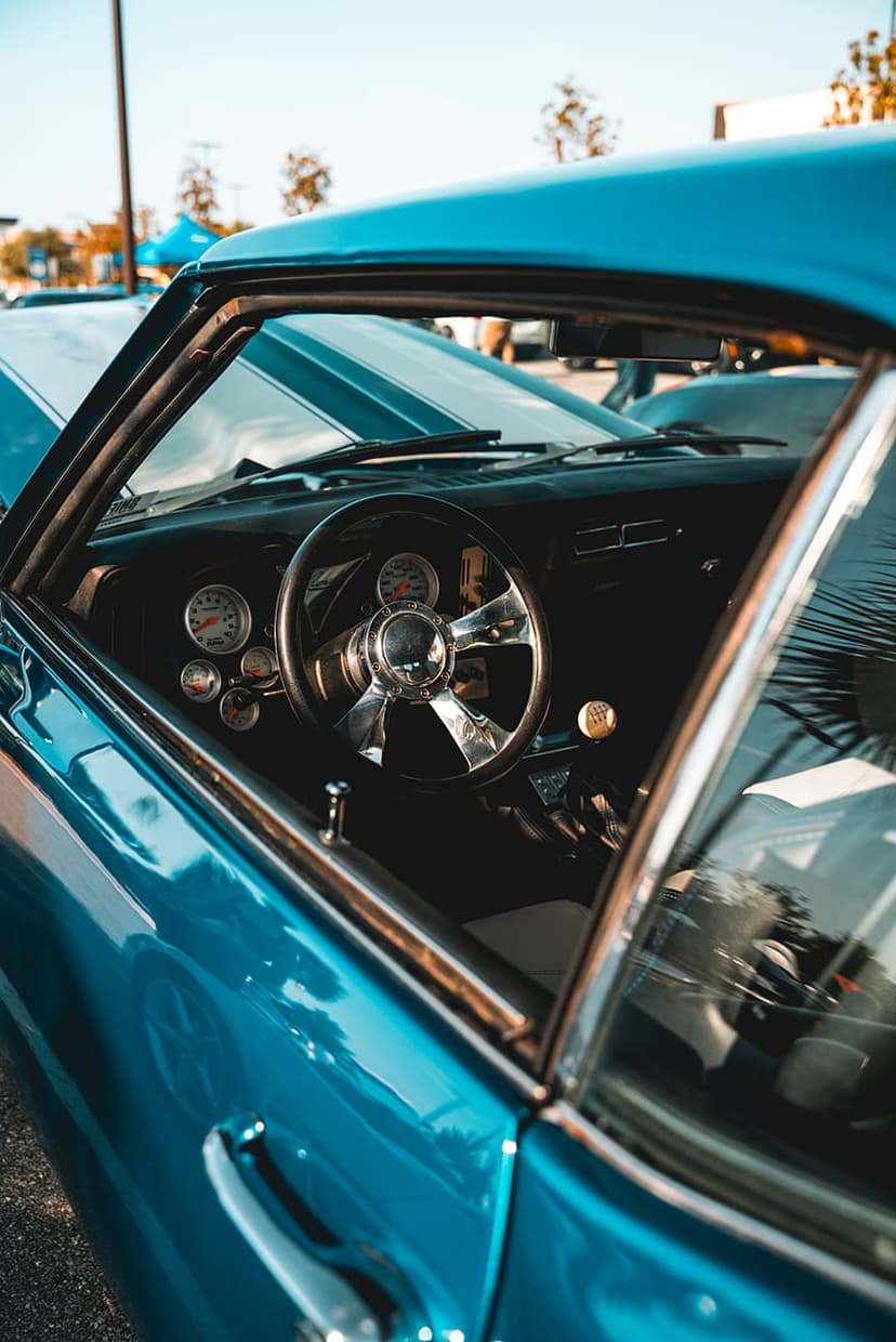 Blue classic car interior featuring a chrome steering wheel with a wood rim and vintage analog dashboard gauges.