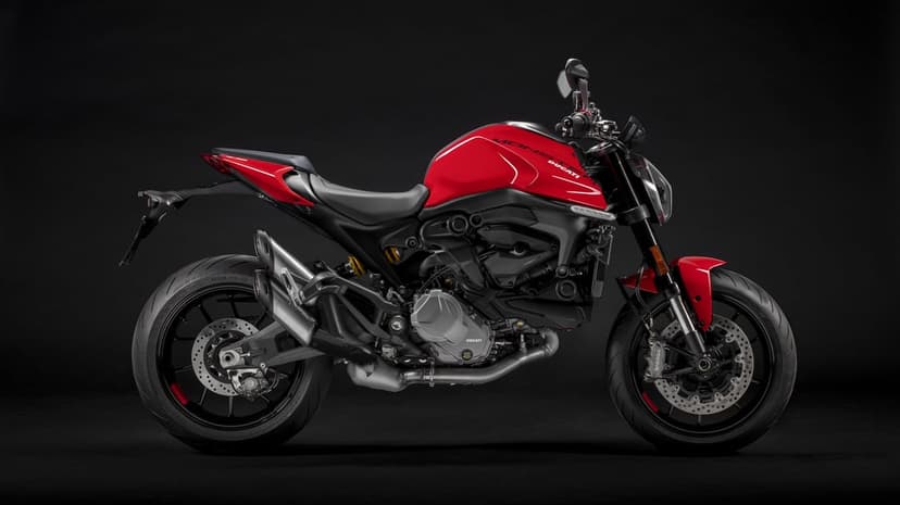Red Ducati Monster motorcycle profile against a black background with professional studio lighting.