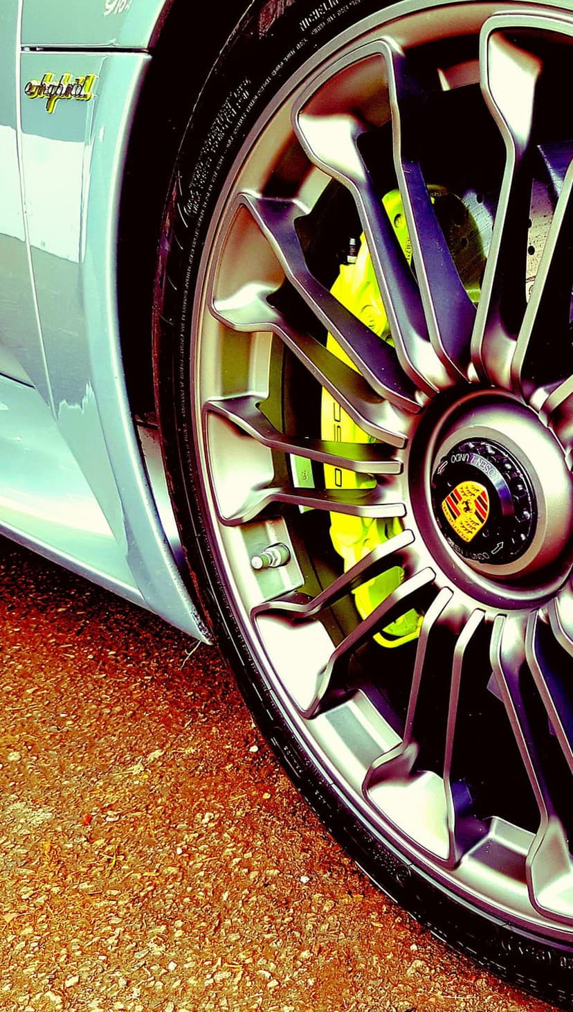 Bright yellow Porsche brake caliper and e-hybrid badge visible through detailed silver alloy wheel spokes.