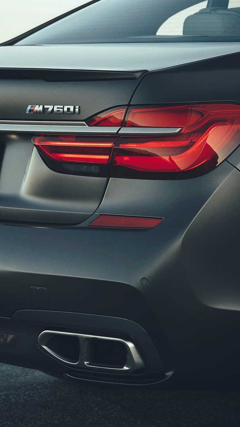 BMW M760Li rear trunk with LED taillights, silver badging, and quad exhaust tips on a matte dark luxury sedan.