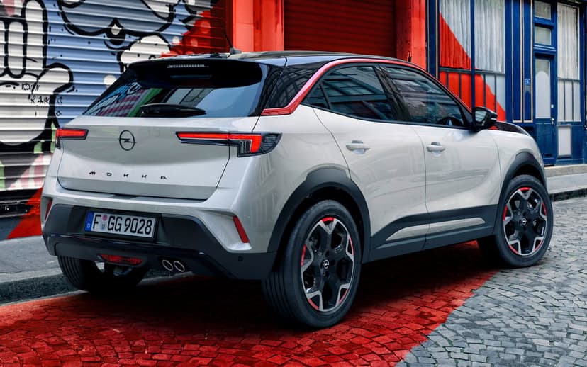 Silver Opel Mokka SUV with red accents parked on red-painted cobblestones beside a vibrant graffiti wall.