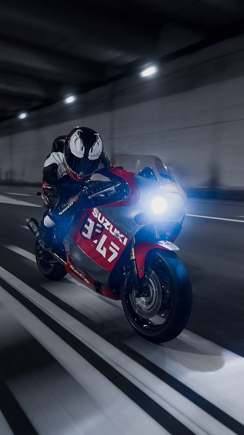 Motorcyclist in a Venom helmet rides a red Suzuki Yoshimura motorcycle through a dark tunnel with motion blur.