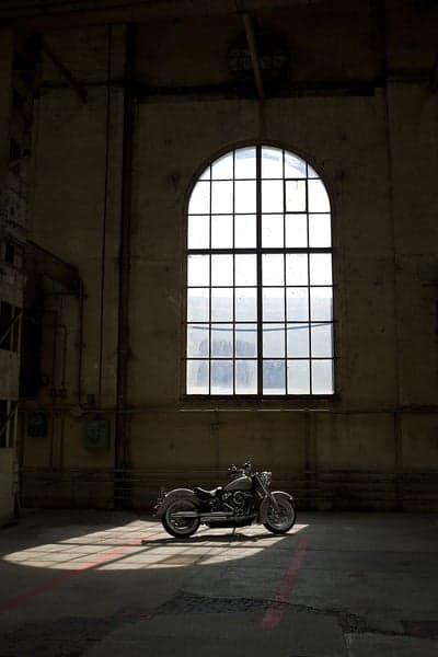 Motorcycle in sunlit industrial warehouse with arched window