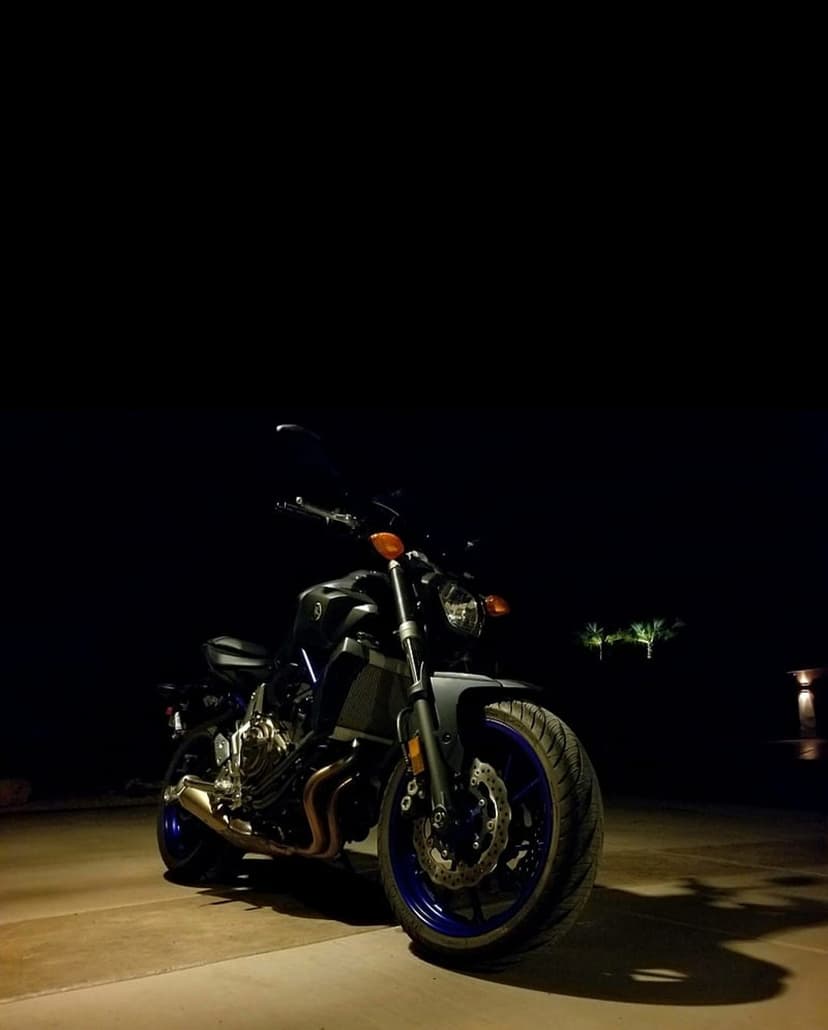 Yamaha MT-07 motorcycle with vibrant blue rims parked outdoors at night, captured from a low-angle perspective.