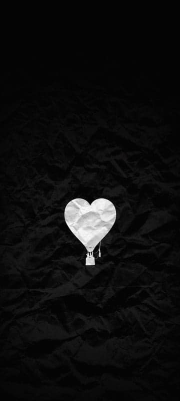 White crumpled paper heart hot air balloon on black background