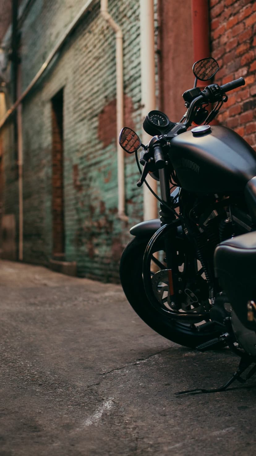 Matte black motorcycle parked in a brick alley with shallow depth of field and urban industrial aesthetic.