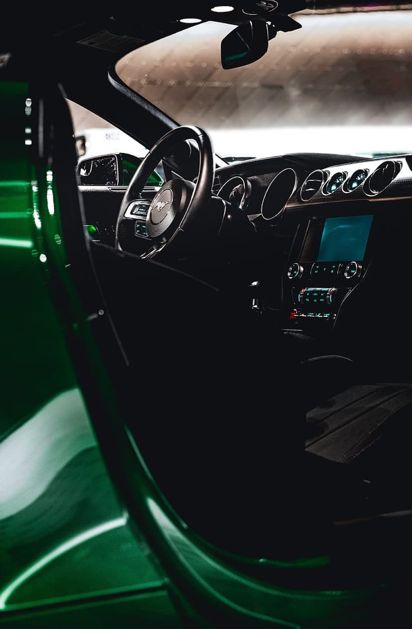 Mustang steering wheel and digital dashboard contrast against a vibrant green car door in this vertical shot.