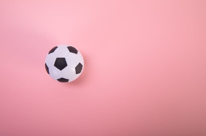 Black and white soccer ball on a solid pink background with a soft shadow cast to the left in a minimalist style.