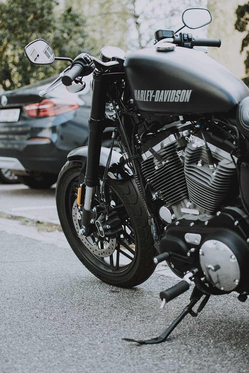 Harley-Davidson motorcycle with a black fuel tank and chrome engine parked on a damp city street during the day.